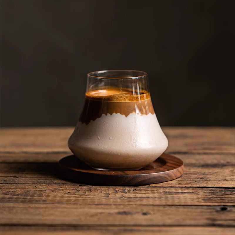丸い木製トレーに置いたガラスカップのカフェラテ